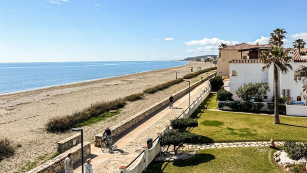 Une vue sur la côte, avec une plage, un chemin pavé et un bâtiment doté d’un toit en tuiles.