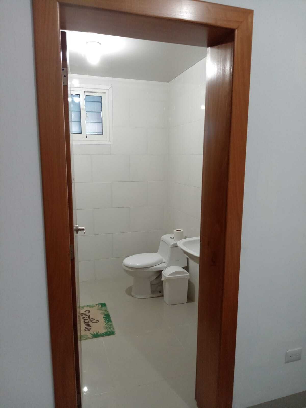 A bathroom with a toilet, sink, and a small window.