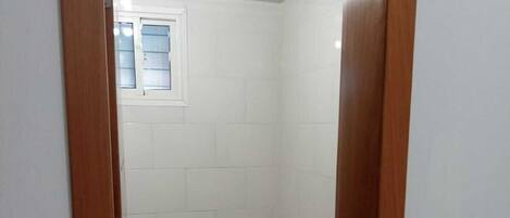 A bathroom with a toilet, sink, and a small window.