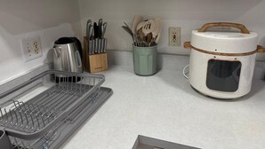 A kitchen with white cabinets, a kettle, a knife block, a spice jar, and a rice cooker. - Lumi House fully equipped house with everything you need for stay. (High Springs)
