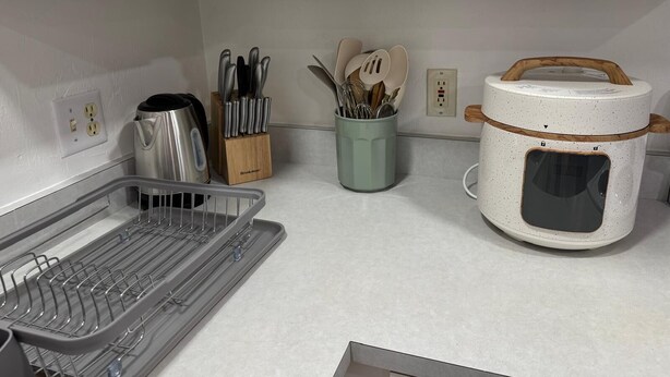 A kitchen with white cabinets, a kettle, a knife block, a spice jar, and a rice cooker. - Lumi House fully equipped house with everything you need for stay. (High Springs)
