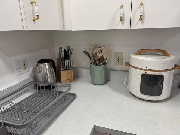 A kitchen with white cabinets, a kettle, a knife block, a spice jar, and a rice cooker. - Lumi House fully equipped house with everything you need for stay. (High Springs)