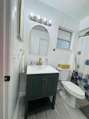 Une salle de bain équipée d’un meuble-lavabo, d’un évier, d’un miroir et de toilettes.