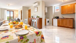 Une cuisine moderne avec des meubles en bois, un coin repas avec une table mise pour le petit-déjeuner et une vue sur l’extérieur.