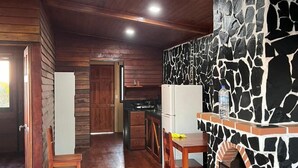 Un interior rústico con chimenea de piedra, suelo de madera y una zona de cocina.