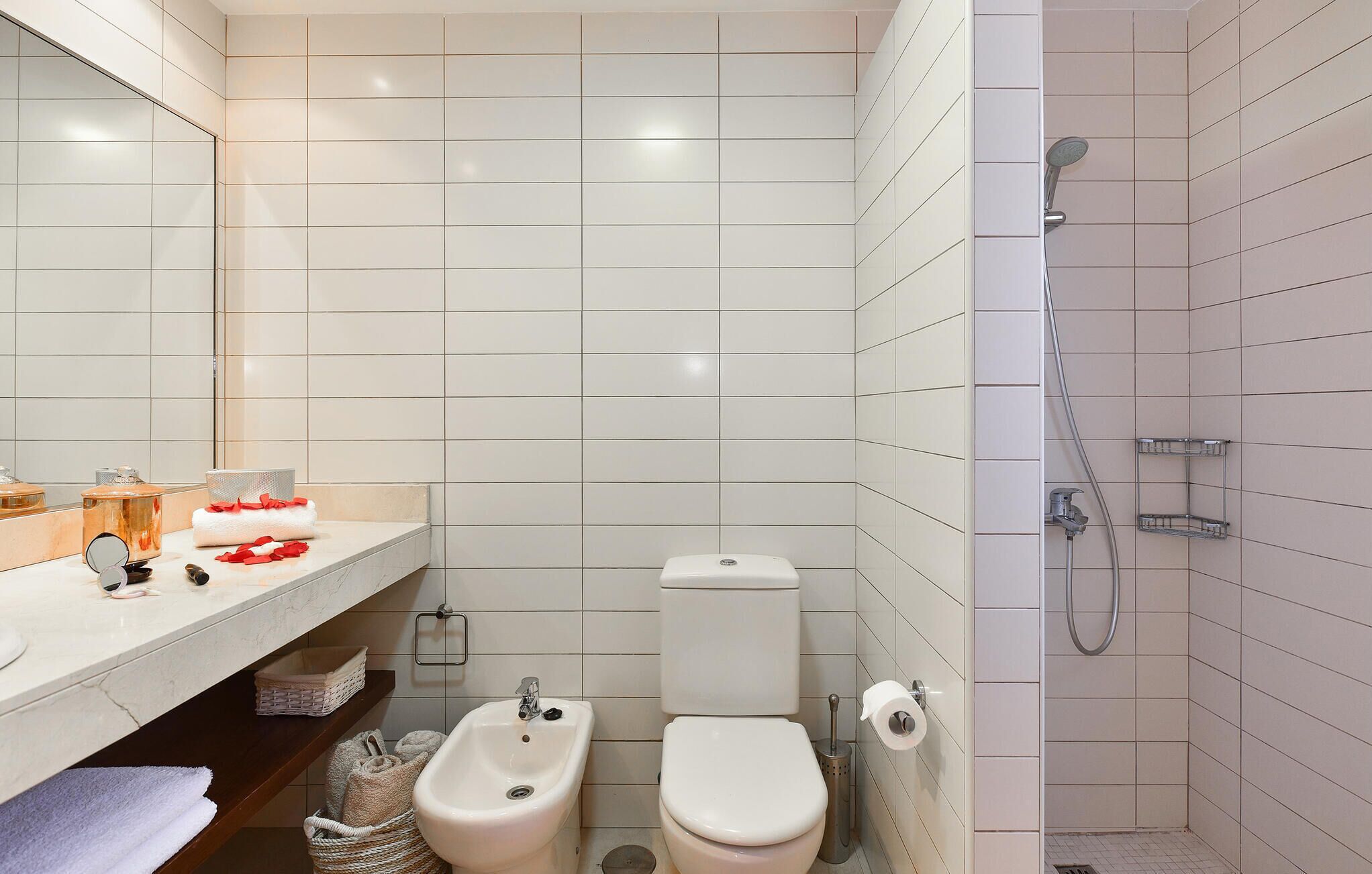 Un baño con inodoro, bidé, lavabo, espejo y ducha.
