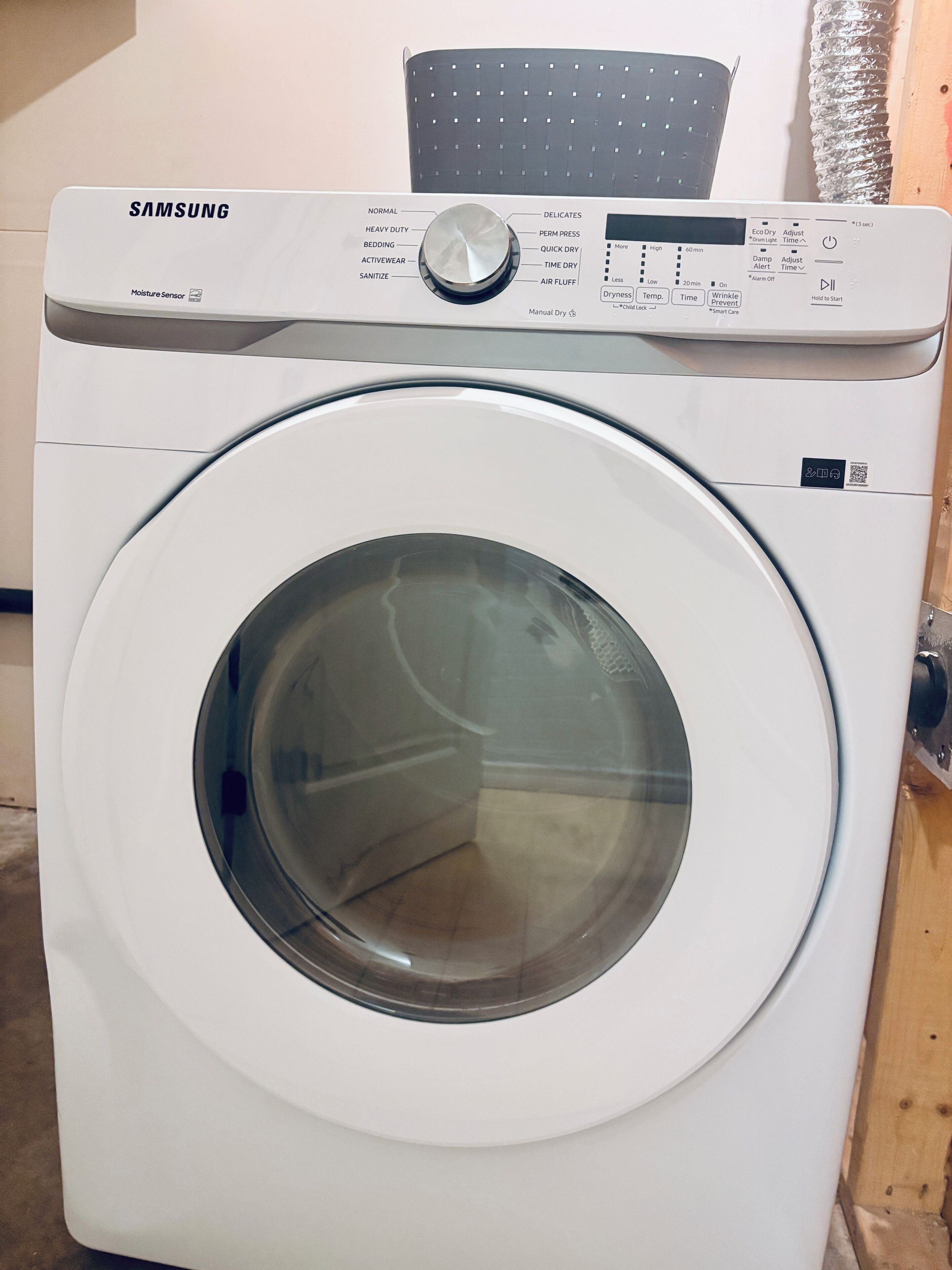 A Samsung washing machine with a moisture sensor, a control panel with various settings, and a QR code.