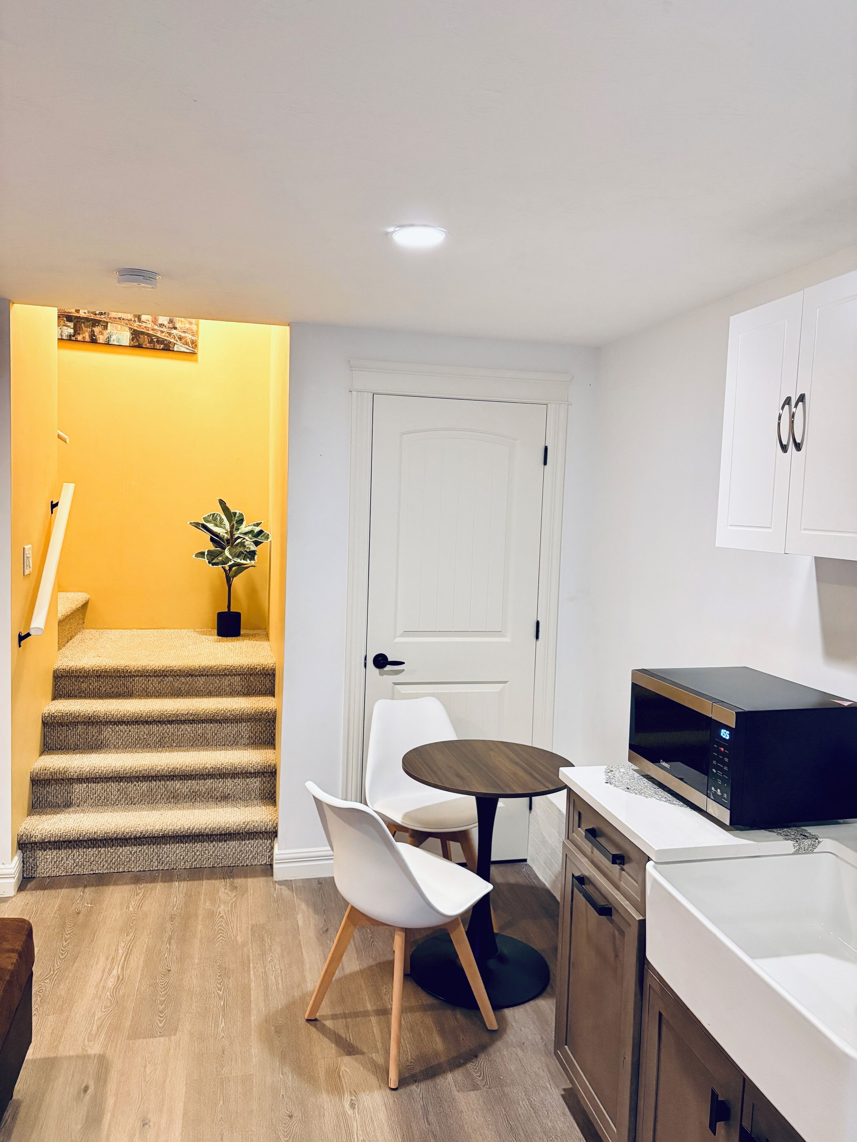 Una cocina moderna con microondas, una pequeña mesa de comedor y una silla.