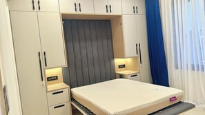A bedroom with a bed, a built-in headboard, bedside tables, and a wardrobe with multiple compartments. - Luxury 2BHK Westside Penthouse, Private Patio & Terrace HiTech City Madhapur HYD (Hyderabad)