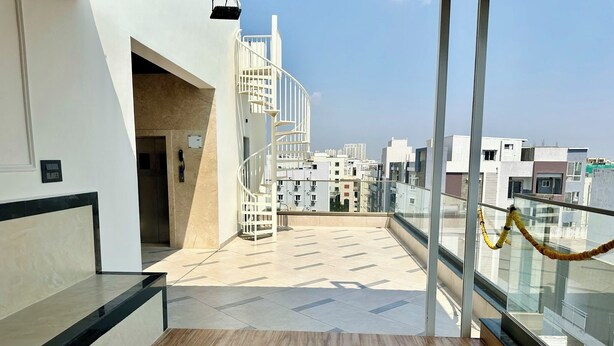A modern interior with a wooden floor, a spiral staircase, and a view of surrounding buildings.