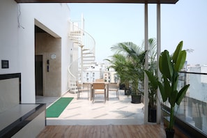 A modern interior with a spiral staircase, a dining area with chairs and a table, and potted plants. - Luxury 2BHK Westside Penthouse, Private Patio & Terrace HiTech City Madhapur HYD (Hyderabad)