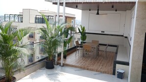 A balcony with potted plants, a wooden table, and chairs.