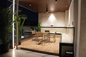 Een moderne eetruimte met een houten tafel en stoelen, een plafondventilator en potplanten.