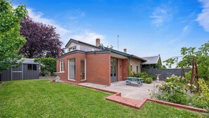 A brick house with a patio, a small shed, and a garden with flowers and a tree. - Character-Filled, Modern Retreat In Mount Pleasant, Ballarat (Mount Pleasant)