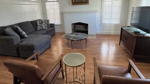 A living room with a sofa, chairs, a coffee table, a fireplace, and a ceiling fan.