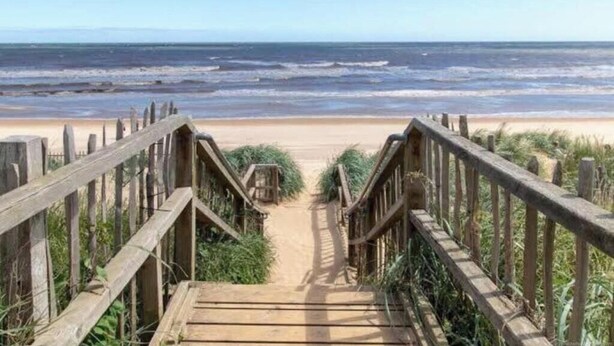 A wooden staircase leading to a sandy beach with the ocean in the background. - Headline:
Seaside Serenity at The Beach House – Your Cozy Escape in Mablethorpe (Mablethorpe)