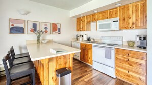 A modern kitchen with wooden cabinets, a white countertop, a built-in microwave, a stove, and a sink. - Mountain Modern Condo + Resort Amenities & Patio (Bend)