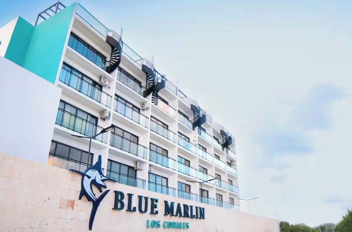 Un hotel de varios pisos con un letrero llamativo que dice 'BLUE MARLIN LOS CORALES'.