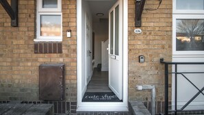 Un pasillo estrecho con una puerta que da a una habitación, un buzón y una placa con un número en la pared.