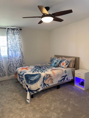 A bedroom with a bed, a ceiling fan, a nightstand, and a window with curtains. - Home in Crystal River FL Water Front/Floating Dock on Deep Water Canal (Crystal River)