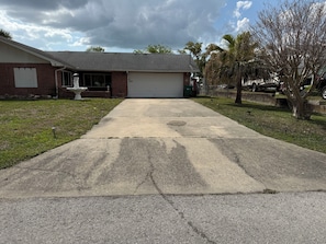 A residential driveway leading to a garage, a brick house, and a small lawn with a statue. - Home in Crystal River FL Water Front/Floating Dock on Deep Water Canal (Crystal River)