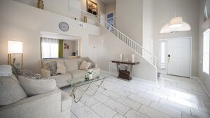 A spacious living room with a high ceiling, a staircase, and a large window. - Welcome to your chic escape North Las Vegas perfect for relaxation and adventure (North Las Vegas)