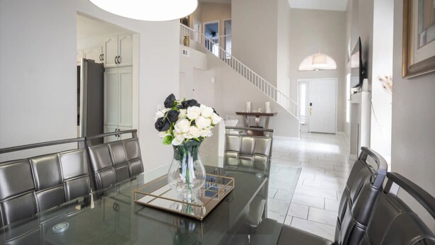 A dining area with a glass table, leather chairs, a vase with flowers, and a staircase in the background. - Welcome to your chic escape North Las Vegas perfect for relaxation and adventure (North Las Vegas)