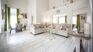 A spacious living room with a sofa set, a glass coffee table, and a dining area with chairs and a table. - Welcome to your chic escape North Las Vegas perfect for relaxation and adventure (North Las Vegas)