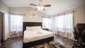 A bedroom with a bed, a ceiling fan, curtains, a nightstand, and a chair. - Welcome to your chic escape North Las Vegas perfect for relaxation and adventure (North Las Vegas)