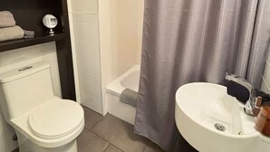 A bathroom with a toilet, sink, and shower curtain. - Urban loft | Rue Saint-Joseph (Québec)