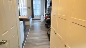 A narrow hallway with a wooden floor, white doors, and a television on a shelf. - Urban loft | Rue Saint-Joseph (Québec)