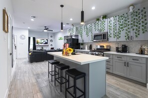 Une cuisine moderne dotée d’un îlot central, de tabourets de bar, d’un four à micro-ondes et d’une cuisinière.
