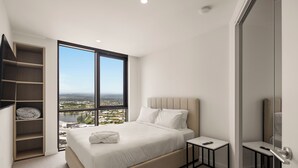 A bedroom with a large window, a bed, a bedside table, and a built-in wardrobe. - Yves Residences - 2204 (Mermaid Beach)