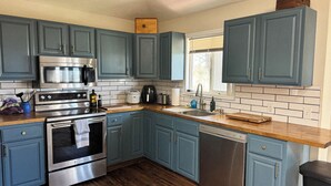 Una cocina con armarios azules, electrodomésticos de acero inoxidable y encimera de madera.