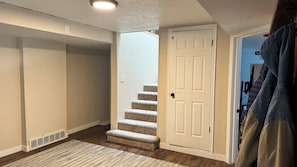 A hallway with a carpeted floor, a white door, and a staircase leading to an upper level. - Cozy Mountain Escape • Firepit, Views, & Wrap Deck (Ogden)