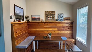 Un rincón acogedor con un banco de madera, una mesita y una pared decorada con diversos objetos, incluyendo un cuadro enmarcado, una colección de monedas y un letrero que dice 'Zimmy's Casino'.