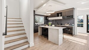 Una cucina moderna con isola centrale, scala in legno e vista all'esterno.