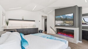 Una camera da letto moderna con un letto, una TV a muro e un caminetto.