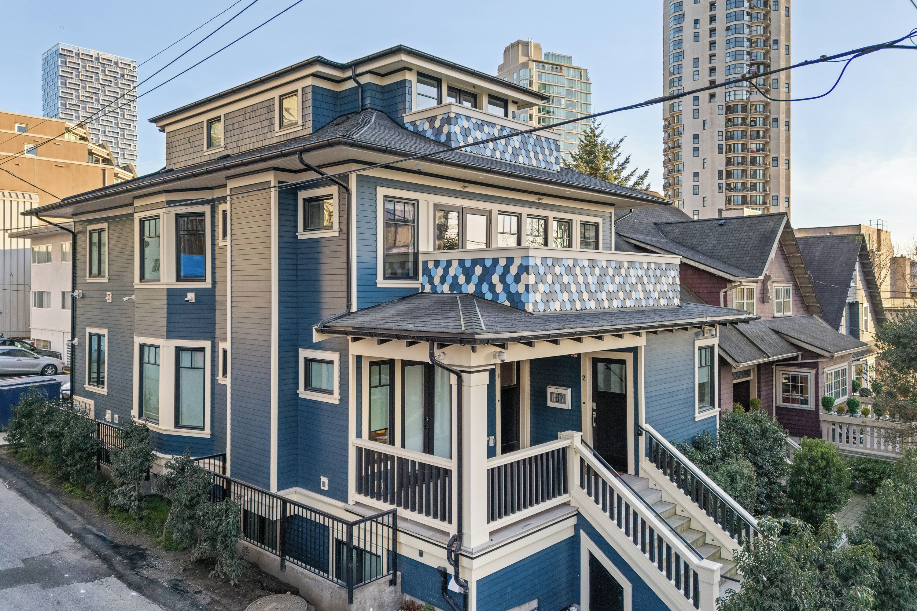 Ein zweistöckiges Haus mit Balkon, einer Veranda und einer Treppe, die zum Eingang führt.