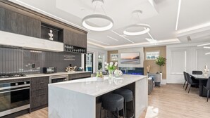Una cucina moderna con isola in marmo, elettrodomestici integrati e illuminazione a sospensione.