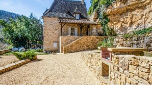A stone house with a sloped roof, a stone staircase, and a gravel driveway. - Charmante maison avec piscine (Castelnaud-la-Chapelle)