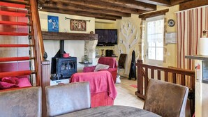 A cozy living room with a fireplace, a television, and a dining area with a table and chairs. - Charmante maison avec piscine (Castelnaud-la-Chapelle)