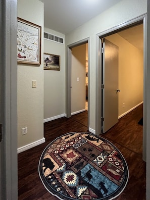 A hallway with a patterned rug, a framed picture, and a door leading to another room. - Spacious DIA House 3BR + Bonus Bed House (Denver)