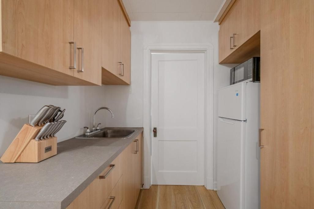 Una cocina compacta con armarios de madera, un lavamanos de acero inoxidable y un refrigerador blanco.