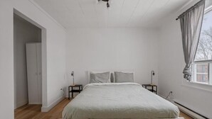Una camera da letto con un letto, un armadio, un comodino e una finestra con tende.