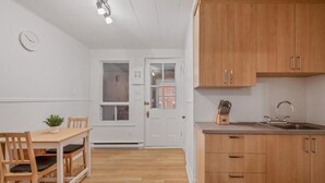 Una cucina con mobili in legno, un lavandino e un'area pranzo con tavolo e sedie.