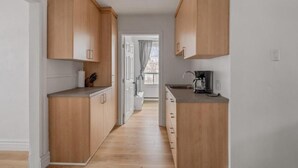 A narrow kitchen with wooden cabinets and a countertop. - Le Petit Cozy, 1 CH, Office, Enfant-Jésus (Québec)