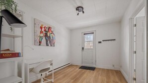 A room with a white desk, chair, and shelves, a door, and a painting on the wall. - Le Petit Cozy, 1 CH, Office, Enfant-Jésus (Québec)