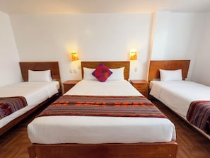 A hotel room with two single beds, a large bed, and a wooden headboard. - Machu Picchu Sacred Valley (Aguas Calientes)