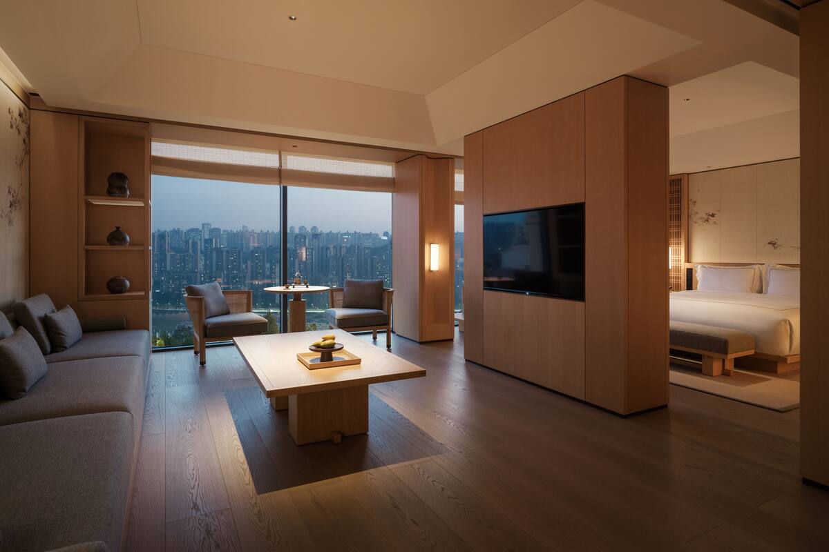 A modern living room with a large window, a flat-screen TV, a sofa, a coffee table, and a city view.
